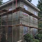A house under construction, surrounded by scaffolding and poles, showcasing the building process in progress.