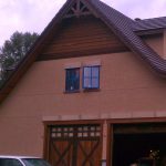 A large brown house featuring two windows and a large door.