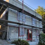 A house under construction, surrounded by scaffolding, showcasing the building process and structural support.