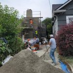 Construction workers are actively installing a new driveway, showcasing teamwork and skilled labor on the site.