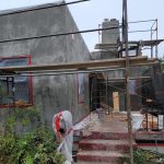 A man is actively working on a house that is currently under construction, focusing on the building process.