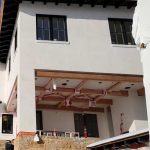 A house under construction on a hillside, showcasing the framework and surrounding natural landscape.