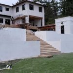 A house featuring a white exterior wall and a set of stairs leading to the entrance.