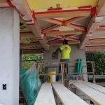 A man is installing fixtures on a ceiling in a building, demonstrating skilled craftsmanship and focus on his work.