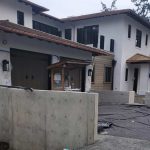 A house under construction with concrete walls, covered by a tarp for protection from the elements.