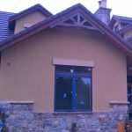 A house featuring a large window and an impressive stone wall, showcasing a blend of modern and rustic architecture.